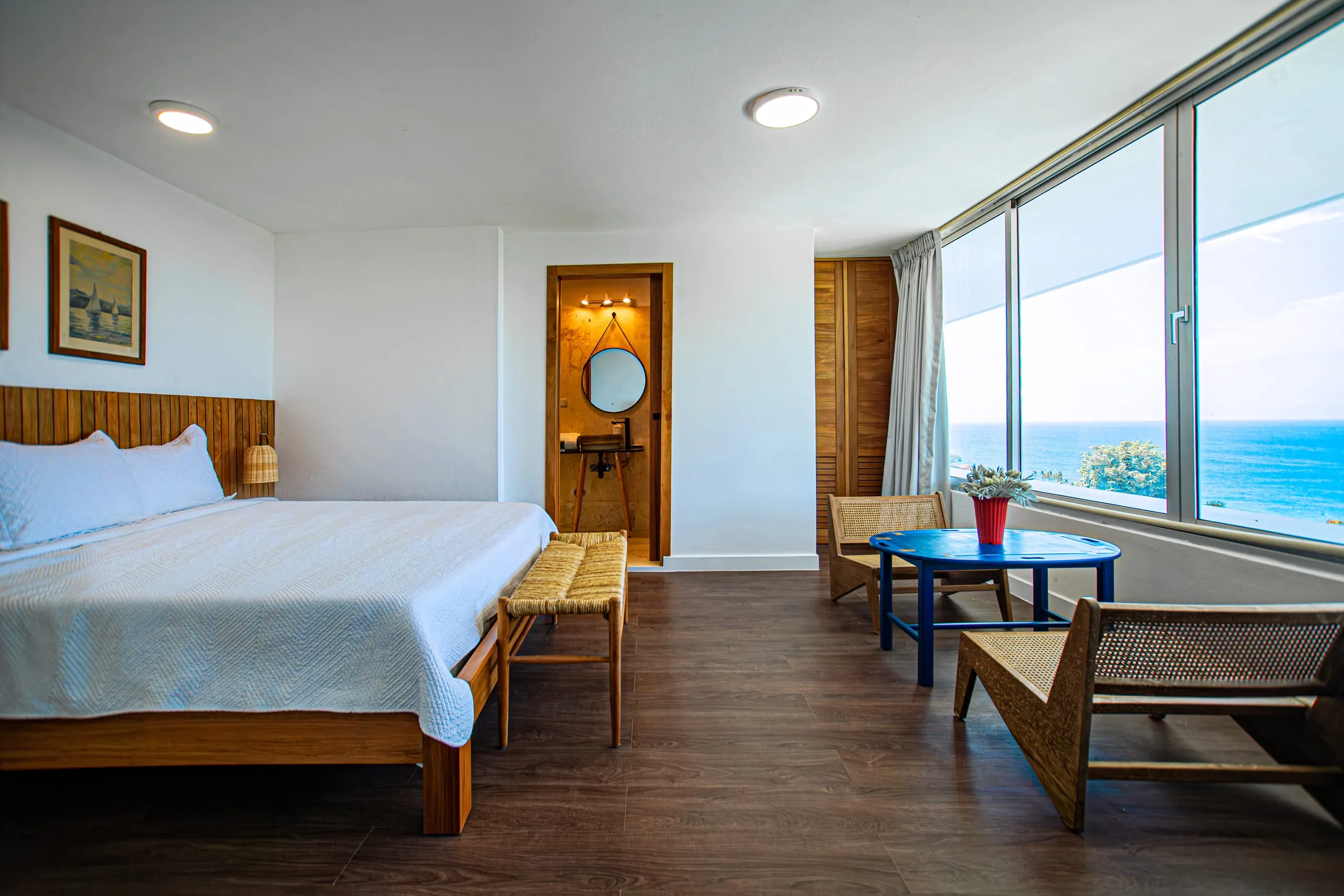 Ocean-view bedroom with a king bed and a sitting corner by the window